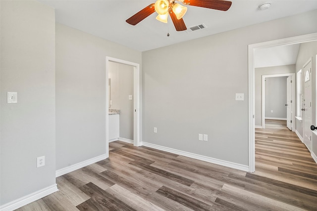 empty room featuring ceiling fan, wood finished floors, visible vents, and baseboards