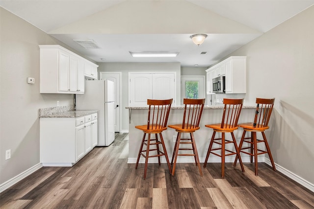 kitchen featuring freestanding refrigerator, white cabinets, stainless steel microwave, and dark wood-style flooring