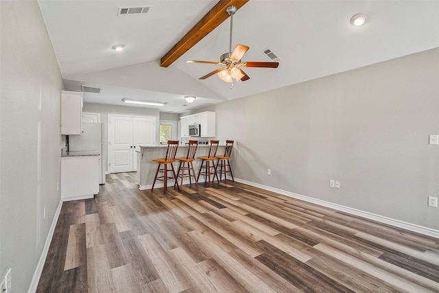 unfurnished living room featuring visible vents, baseboards, and wood finished floors