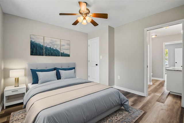 bedroom with a ceiling fan, baseboards, and wood finished floors