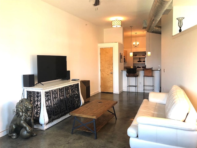 living area featuring a notable chandelier, finished concrete flooring, and baseboards