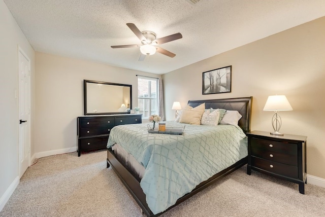 bedroom featuring a ceiling fan, baseboards, a textured ceiling, and light colored carpet