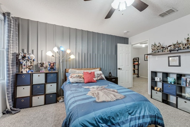 bedroom featuring a textured ceiling, ceiling fan with notable chandelier, carpet, and visible vents