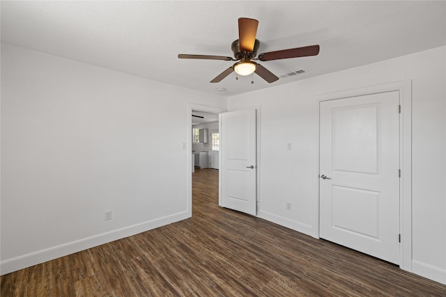 unfurnished bedroom featuring dark wood-style floors, baseboards, visible vents, and a ceiling fan