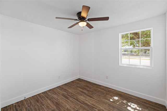 empty room with ceiling fan, baseboards, and dark wood finished floors