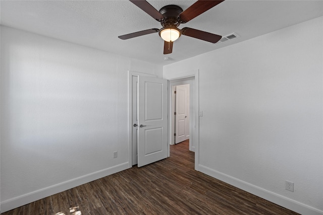 spare room featuring dark wood-type flooring, visible vents, baseboards, and a ceiling fan