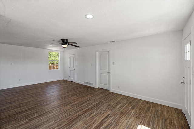 empty room with dark wood-style floors, visible vents, and baseboards