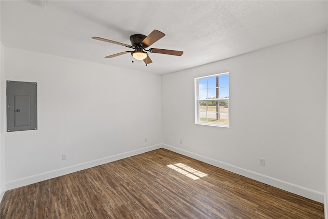 empty room with electric panel, a textured ceiling, baseboards, and wood finished floors