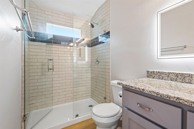 bathroom with vanity, a shower stall, and toilet