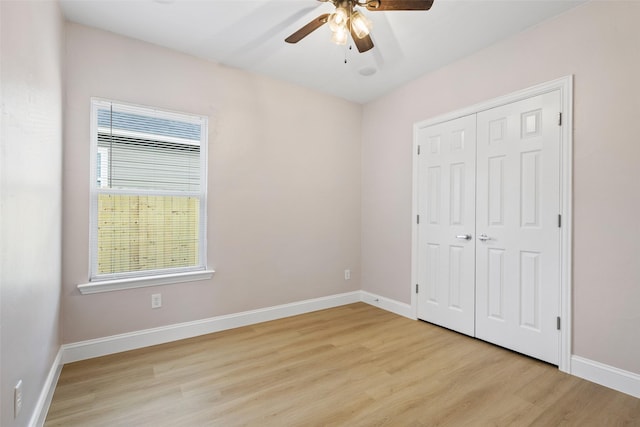 unfurnished bedroom featuring multiple windows, light wood-type flooring, and baseboards