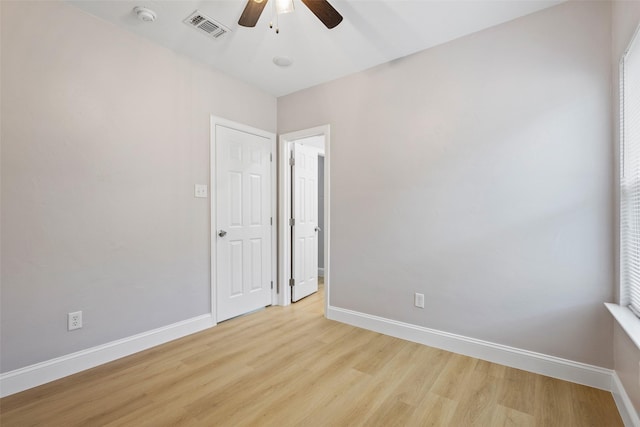 unfurnished room with a ceiling fan, light wood-type flooring, visible vents, and baseboards