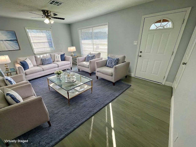 living room featuring wood finished floors, healthy amount of natural light, ceiling fan, a textured ceiling, and baseboards
