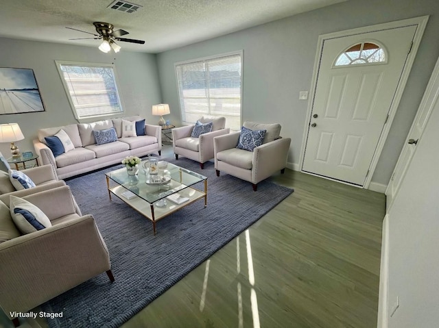 living room with a textured ceiling, visible vents, a wealth of natural light, and wood finished floors