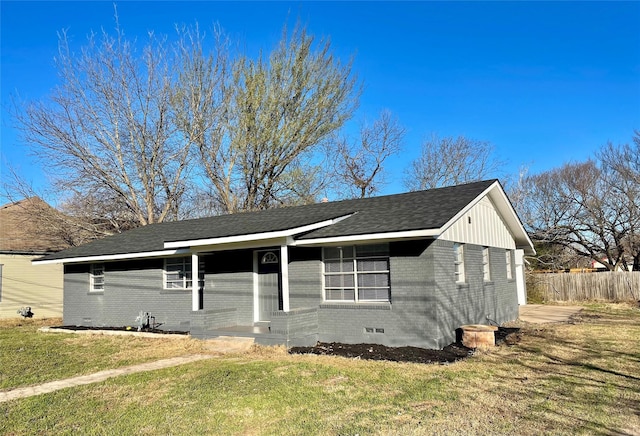 view of front facade with brick siding, roof with shingles, crawl space, fence, and a front yard