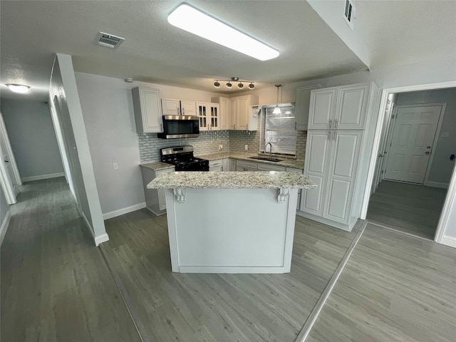 kitchen with a sink, visible vents, light wood-style floors, stainless steel microwave, and gas stove