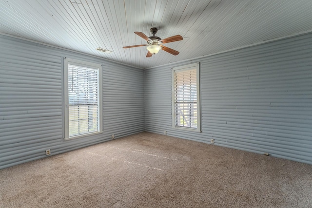 carpeted spare room featuring a healthy amount of sunlight, visible vents, and a ceiling fan