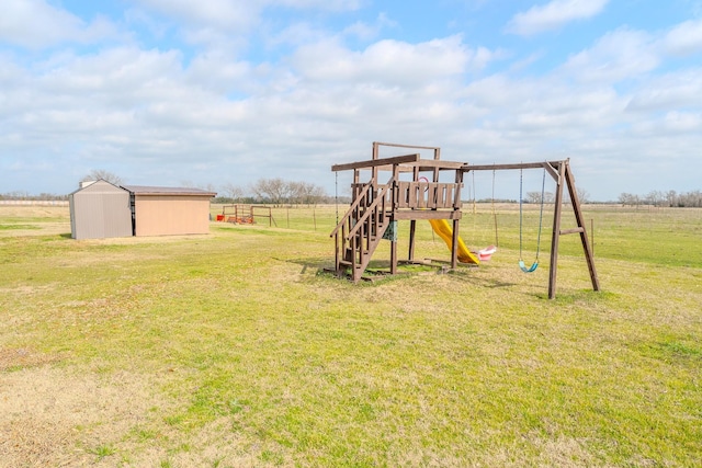 view of playground with an outbuilding, a rural view, and a yard