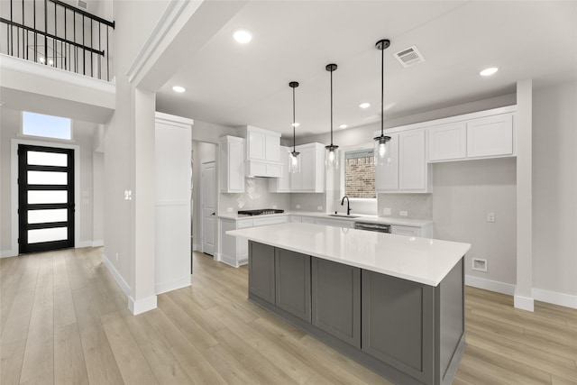 kitchen featuring baseboards, light countertops, white cabinets, gas stovetop, and a sink