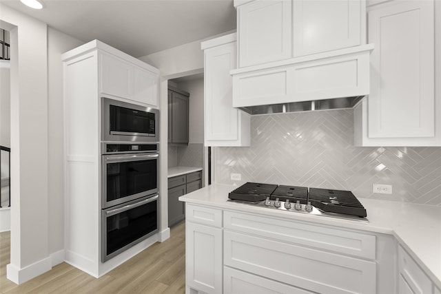 kitchen featuring light wood-style flooring, tasteful backsplash, appliances with stainless steel finishes, and light countertops