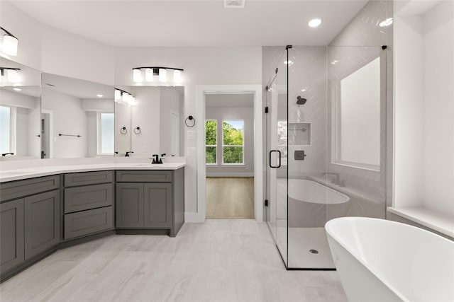 full bathroom featuring a shower stall, marble finish floor, double vanity, and a soaking tub