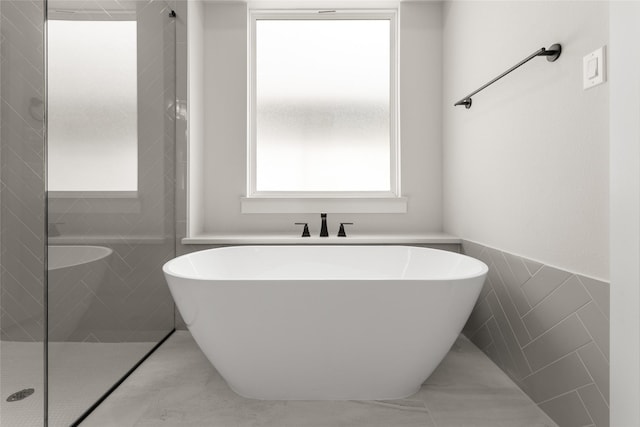 full bath featuring a freestanding bath, tile walls, and a tile shower