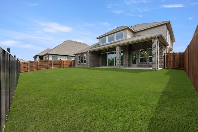 back of house with brick siding, a fenced backyard, and a lawn