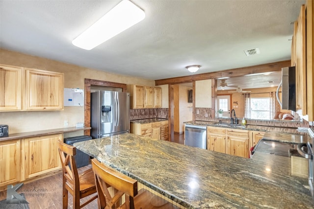 kitchen featuring visible vents, light brown cabinetry, appliances with stainless steel finishes, a sink, and a peninsula