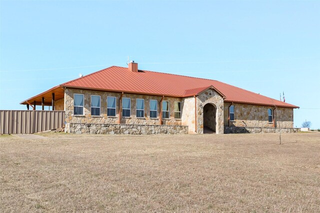 back of property with a chimney, stone siding, and metal roof