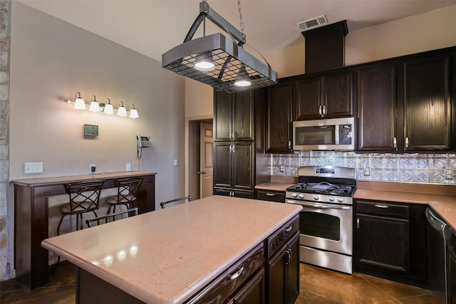 kitchen featuring visible vents, a kitchen island, light countertops, decorative backsplash, and appliances with stainless steel finishes