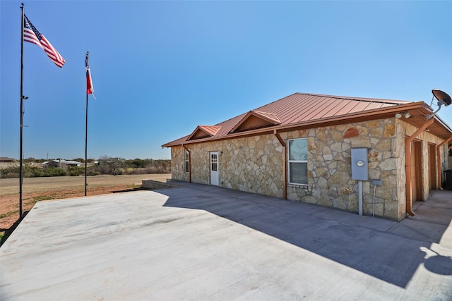 exterior space featuring a standing seam roof, metal roof, and stone siding