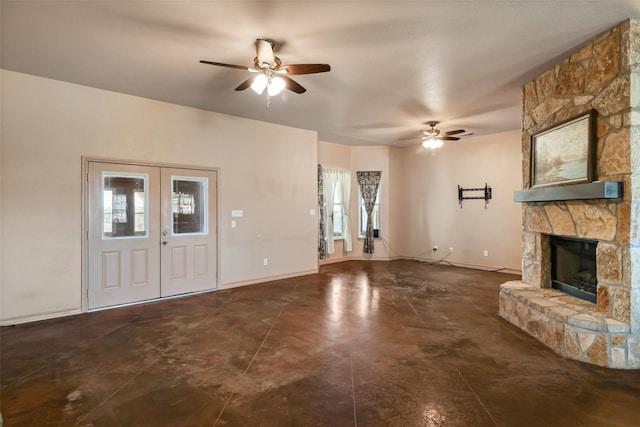unfurnished living room with baseboards, ceiling fan, french doors, and a stone fireplace