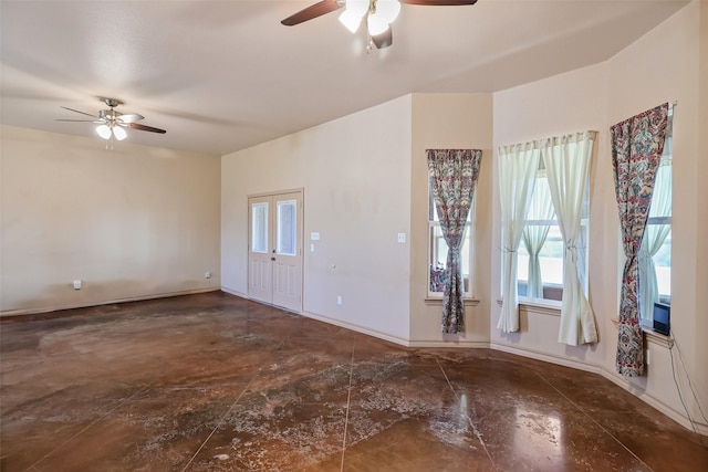 interior space featuring a ceiling fan, baseboards, and concrete floors