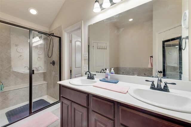 full bathroom with vaulted ceiling, double vanity, a stall shower, and a sink