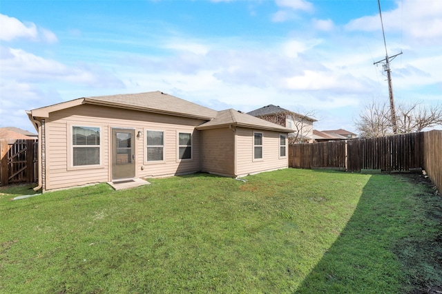 back of house with a fenced backyard and a yard