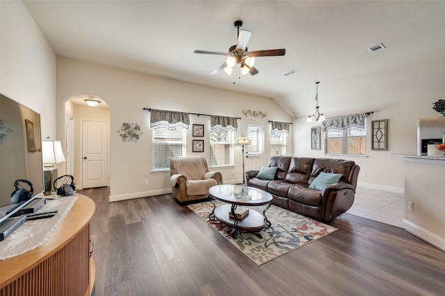 living room featuring arched walkways, visible vents, vaulted ceiling, and wood finished floors