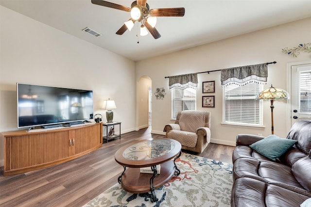 living area featuring baseboards, visible vents, arched walkways, ceiling fan, and wood finished floors