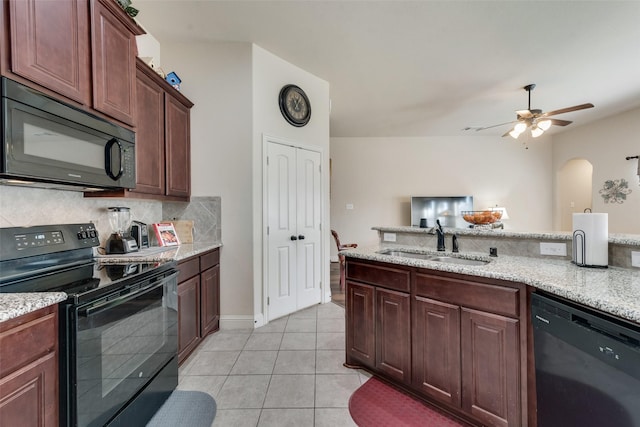 kitchen with tasteful backsplash, light tile patterned flooring, a sink, light stone countertops, and black appliances