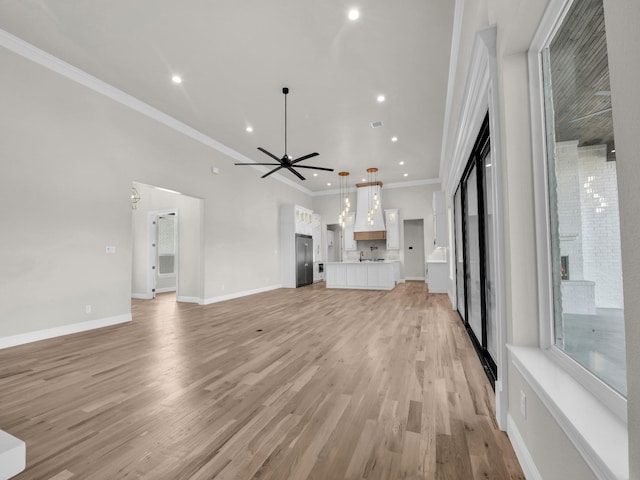 unfurnished living room featuring baseboards, a ceiling fan, ornamental molding, light wood-type flooring, and recessed lighting