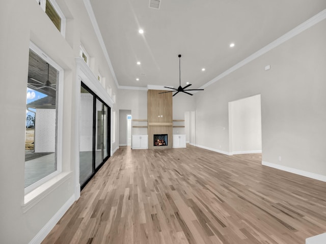 unfurnished living room featuring a large fireplace, light wood-type flooring, a ceiling fan, and baseboards