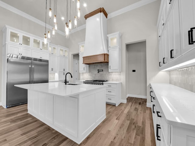 kitchen featuring light wood-style flooring, white cabinets, custom exhaust hood, stainless steel built in refrigerator, and crown molding