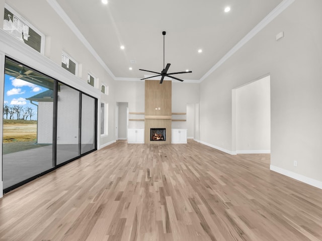 unfurnished living room with light wood-style flooring, a fireplace, a ceiling fan, and crown molding