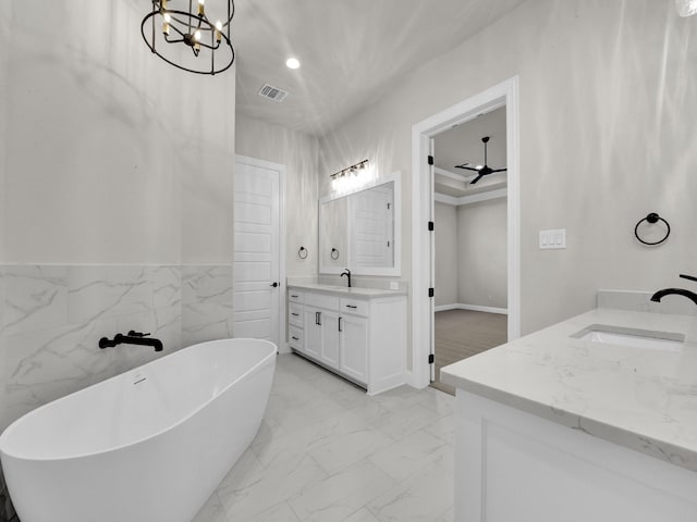 bathroom with marble finish floor, two vanities, visible vents, a sink, and a freestanding tub