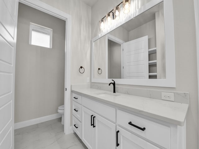 bathroom featuring toilet, marble finish floor, baseboards, and vanity