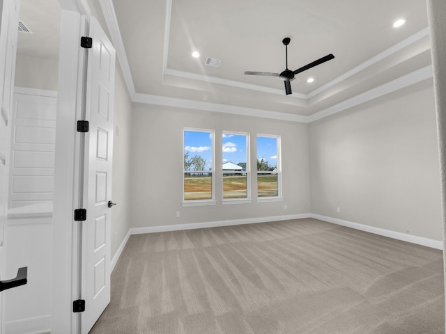 spare room featuring crown molding, a tray ceiling, and baseboards