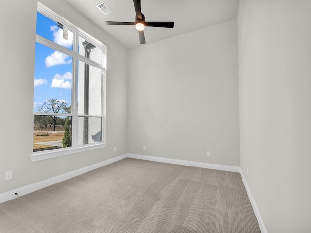 carpeted spare room with a ceiling fan, visible vents, plenty of natural light, and baseboards