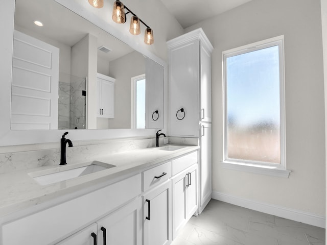 bathroom with marble finish floor, a marble finish shower, baseboards, and a sink