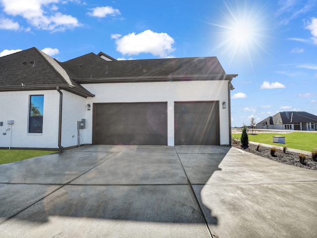 exterior space with driveway, a shingled roof, an attached garage, a front yard, and brick siding