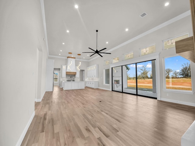 unfurnished living room featuring light wood-style floors, baseboards, crown molding, and recessed lighting