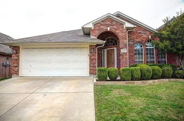 view of front of house featuring a garage, concrete driveway, brick siding, and a front lawn