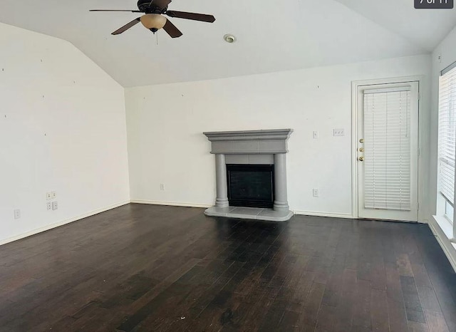 unfurnished living room with lofted ceiling, a fireplace with raised hearth, ceiling fan, wood finished floors, and baseboards